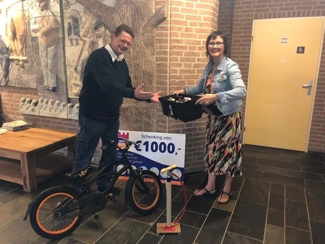 foto overhandiging fietsreparatieset van petra wevers aan mathy baaijens