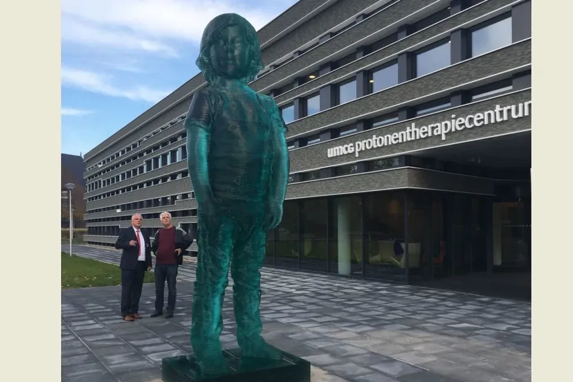 het reuzenkind voor het protonentherapiecentrum van het umcg met daarachter bestuursvoorzitter jos aartsen links en kunstenaar herman lamers e1539451517551