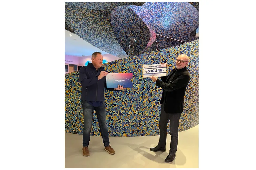 medewerker van de vriendenloterij reikt cheque uit aan andreas bluhm directeur van het groninger museum