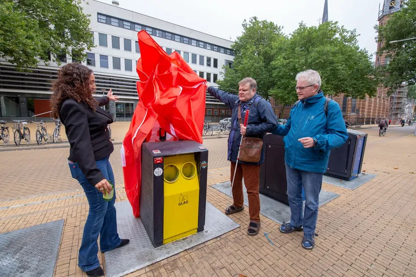 wethouder chakor onthult brailleplaatjes op ondergrondse glascontainer op de rademarkt