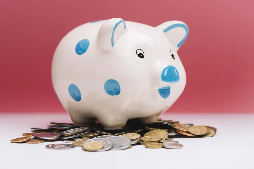 spotted ceramic piggybank coins front red background