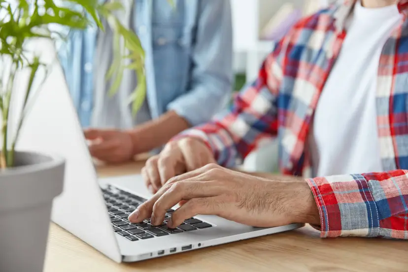 cropped-shot-two-male-bloggers-type-publication-laptop-computer-use-laptop-computer-sit-wooden-desk-young-prosperous-bussinessmen-check-mail-send-feedbacks-connected-wifi