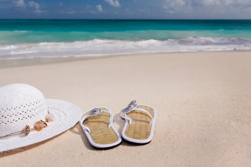 hat and flip flops on the beach