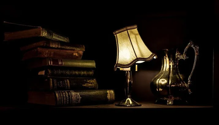 ancient lamp with silver jug and books on table