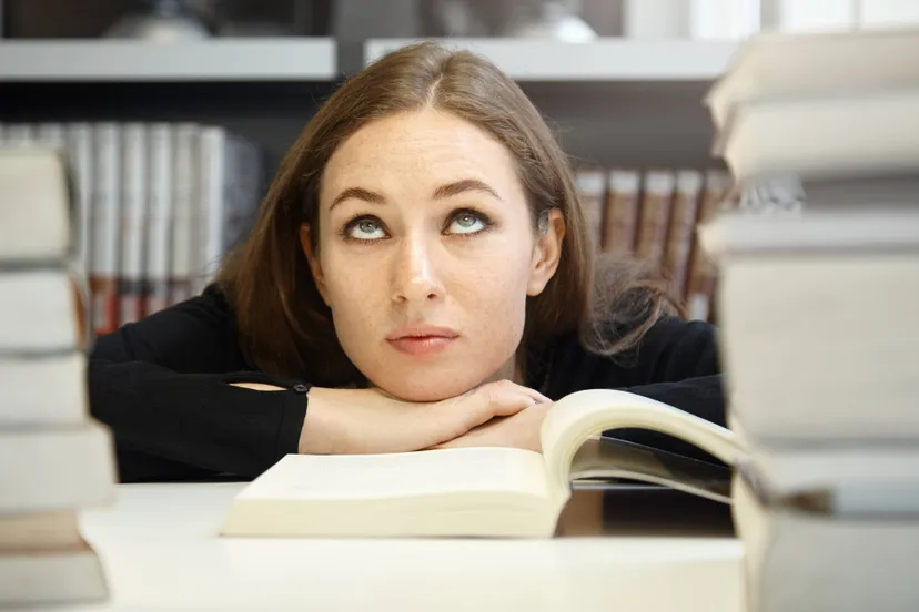 cute-brunette-student-woman-black-jacket-studying-reading-textbook-manual-university-library-having-hard-time-understanding-material-rolling-her-eyes-looking-bored-confused