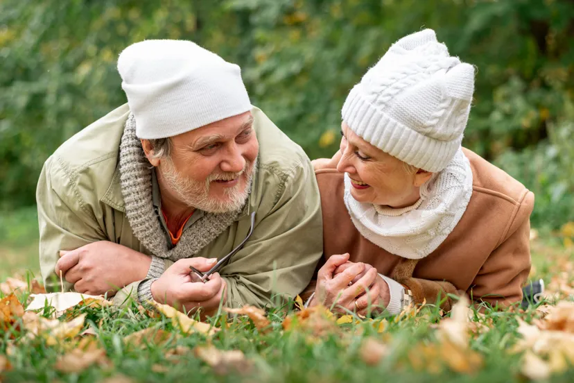 low-angle-senior-couple-sitting-field-with-leaves