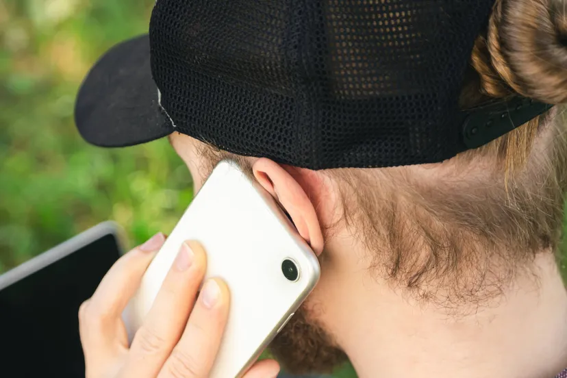 man-is-talking-smartphone-while-sitting-grass-with-laptop