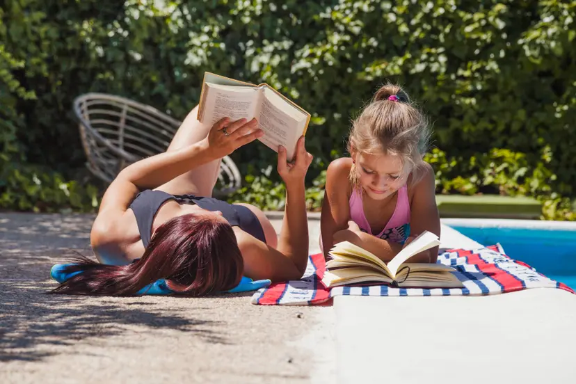 mother-daughter-lying-poolside-reading