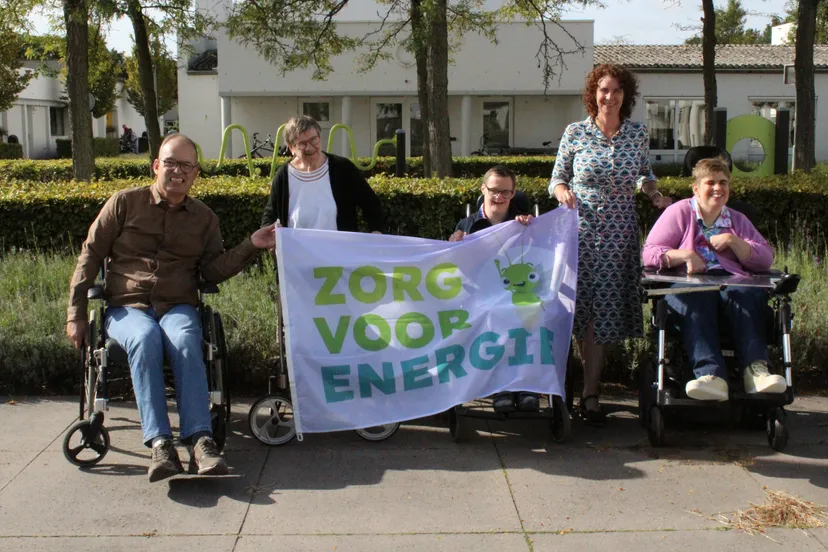 bestuurder vera hersbach houdt samen met bewoners de campagnevlag in de lucht