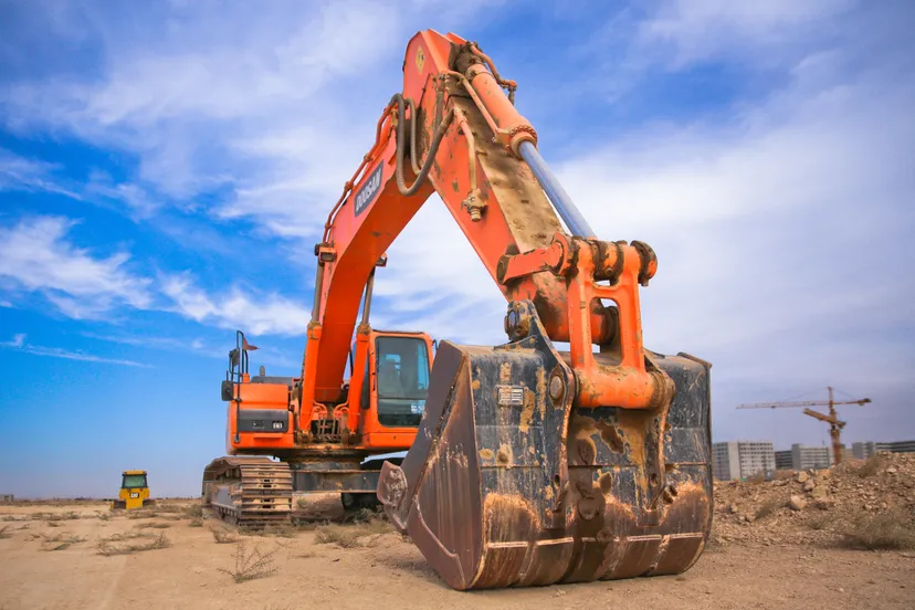 low angle photography of orange excavator under white clouds 1078884