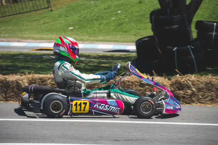 man in racing suit with helmet riding go kart 724704