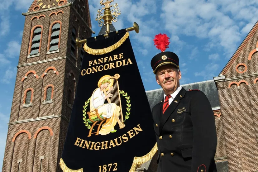 fanfare concordia einighausen vaandeldrager met vaandel bij de kerk
