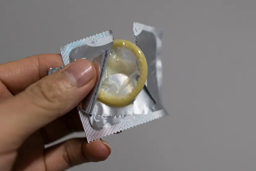 geopende condoomverpakking in hand