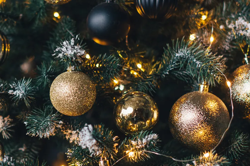 kerstboom versierd met slingers en gouden ballen op een donkere muur