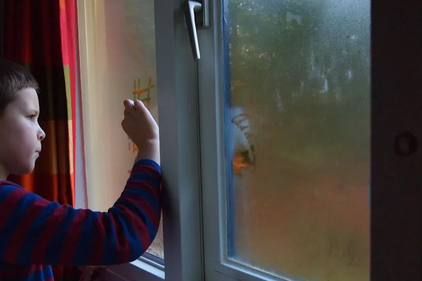 kind tekent op beslagen raam
