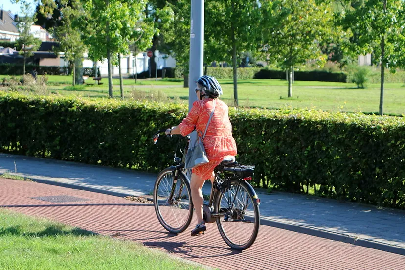oudere vrouw met fietshelm op elektrische fiets 1