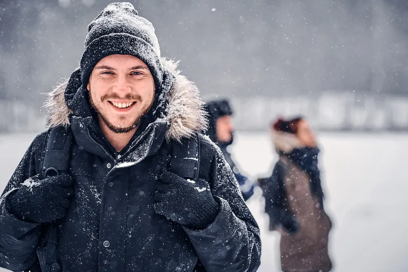 portret van een gelukkige wandelaar met een rugzak die met zijn vrienden door een winterbos loopt