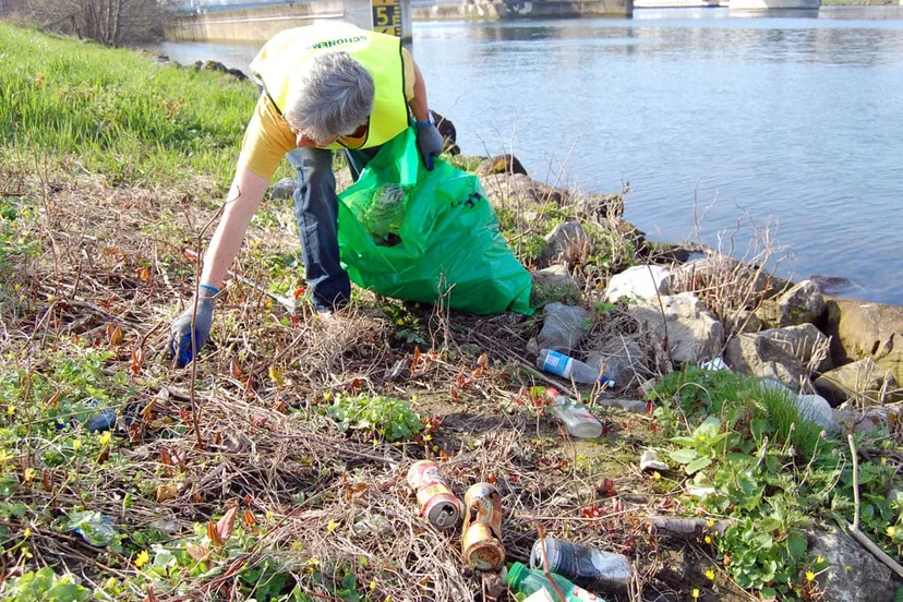 vrijwilliger ruimt afval op aan maasoever