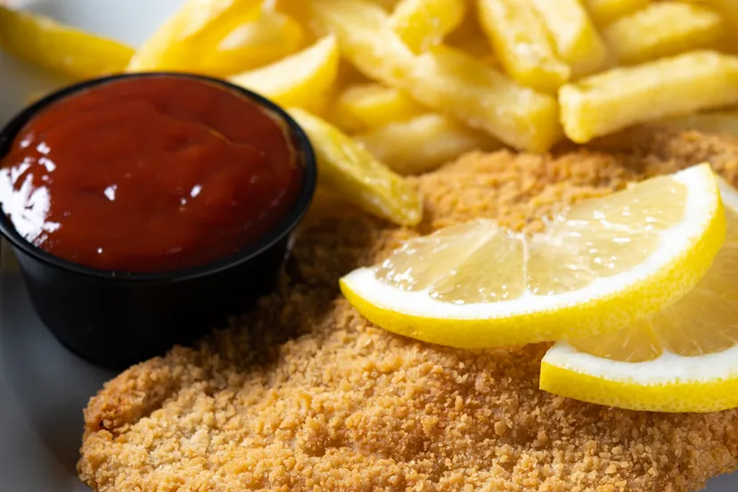 wiener schnitzel met gebakken aardappelen op houten tafel