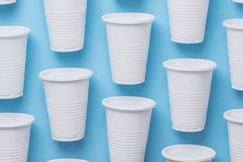 witte plastic bekers voor eenmalig gebruik op een blauwe achtergrond