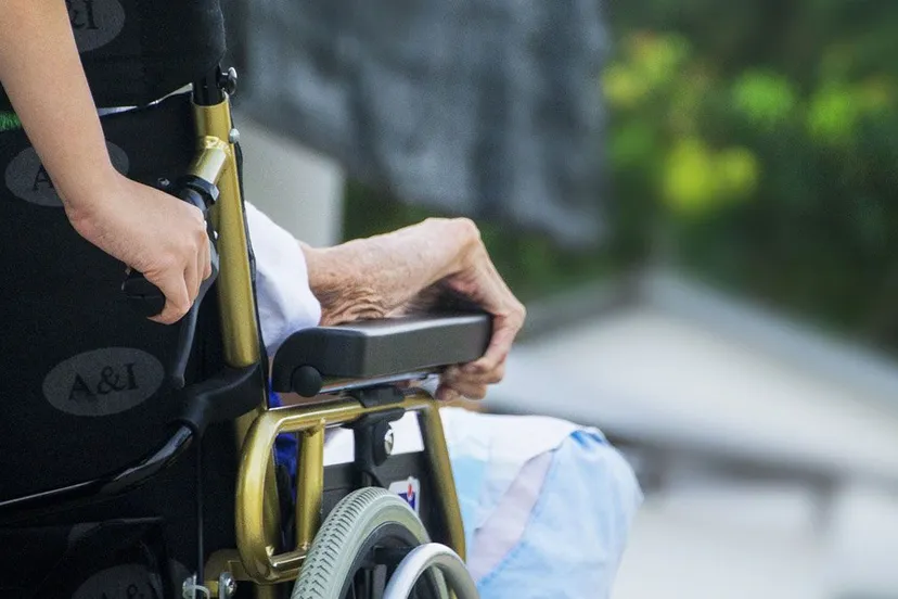 mantelzorg persoon duwt rolstoel met zorgvragende