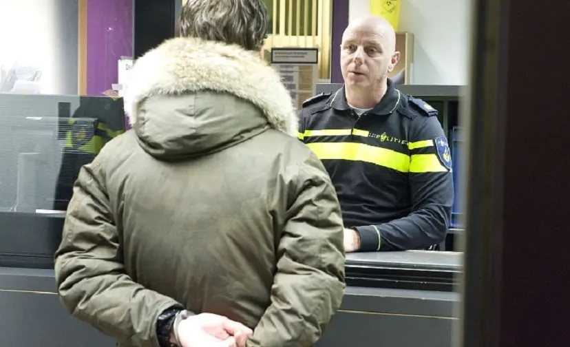 arrestant voor de balie in gesprek met agent