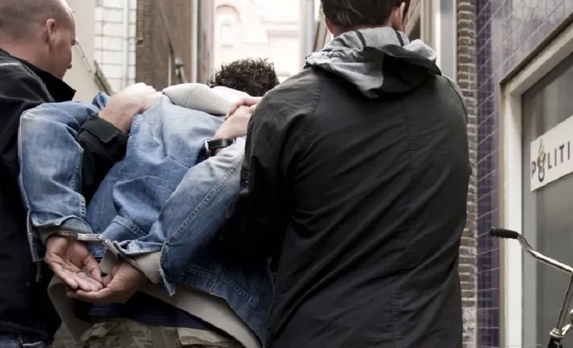 man wordt geboeid afgevoerd
