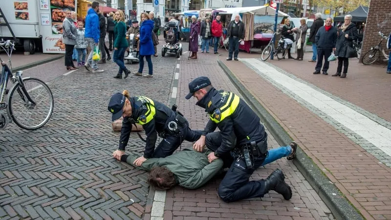 twee agenten drukken verdachte tegen de grond