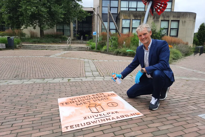 foto wethouder erik volmerink brengt de eerste sjabloon op straat aan