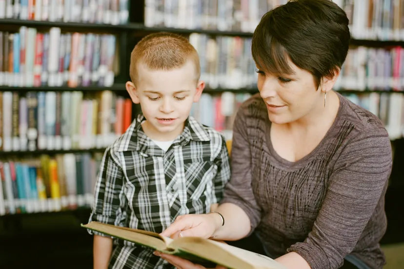 moeder zoontje boek bibliotheek lezen kijken