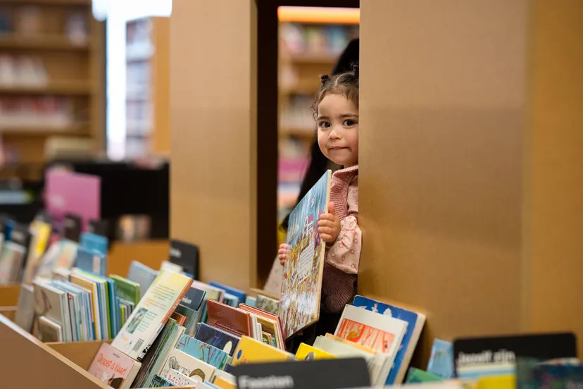 TON_6179.meisje_peuter_bieb_bibliotheek_prentenboeken_bak_kijken_boek_pakken