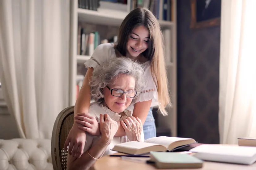 oma_bejaarde_kleindkind_meisje_knuffel_tafel_boeken_lezen