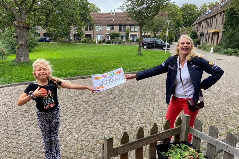 een dolblije elize met de cheque van het vriendenfonds van de vriendenloterij 1