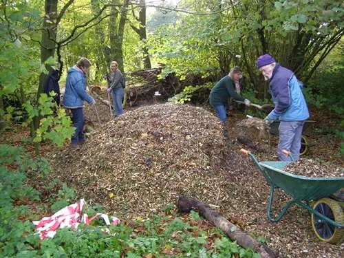 vrijwilligers scheppen houtsnippers
