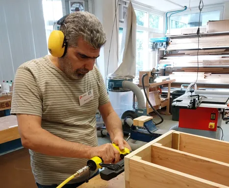 deelnemer ibrahim van het praktijkverklaringstraject aan de slag in de houtwerkplaats met de constructie van egelhuizen foto stichting piezo