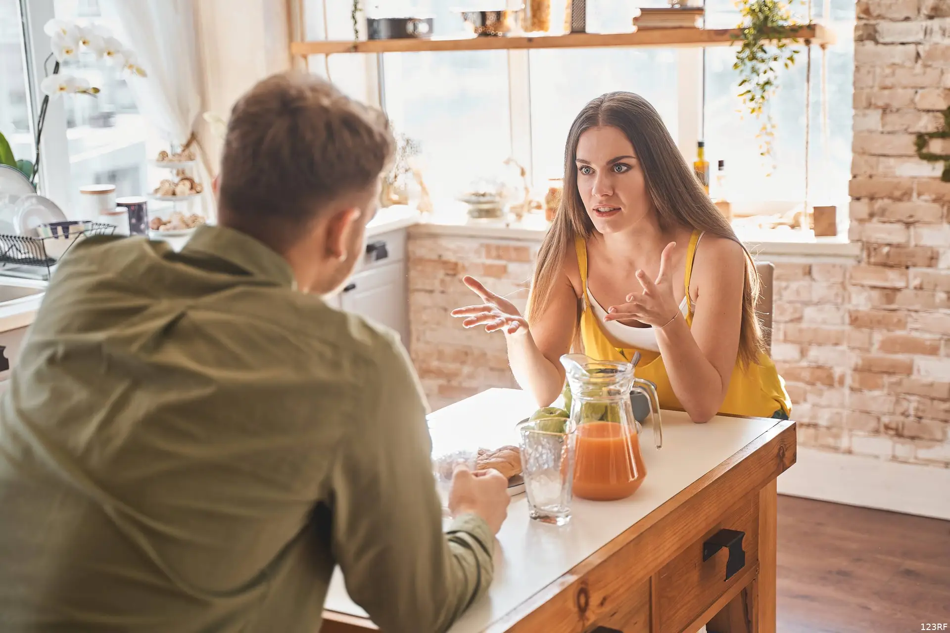 Emotionele jonge vrouw actief gesticuleren tijdens het praten met haar vriend.