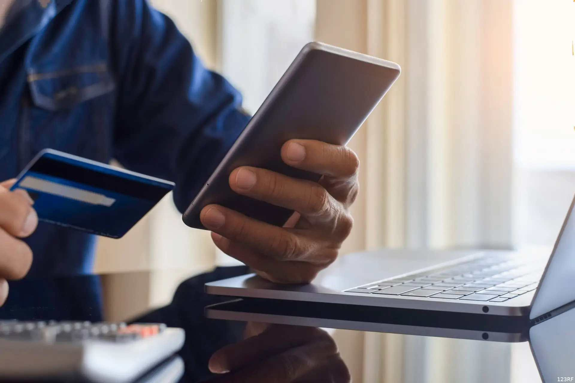 Iemand houdt een bankpas tegen de achterkant van een smartphone.