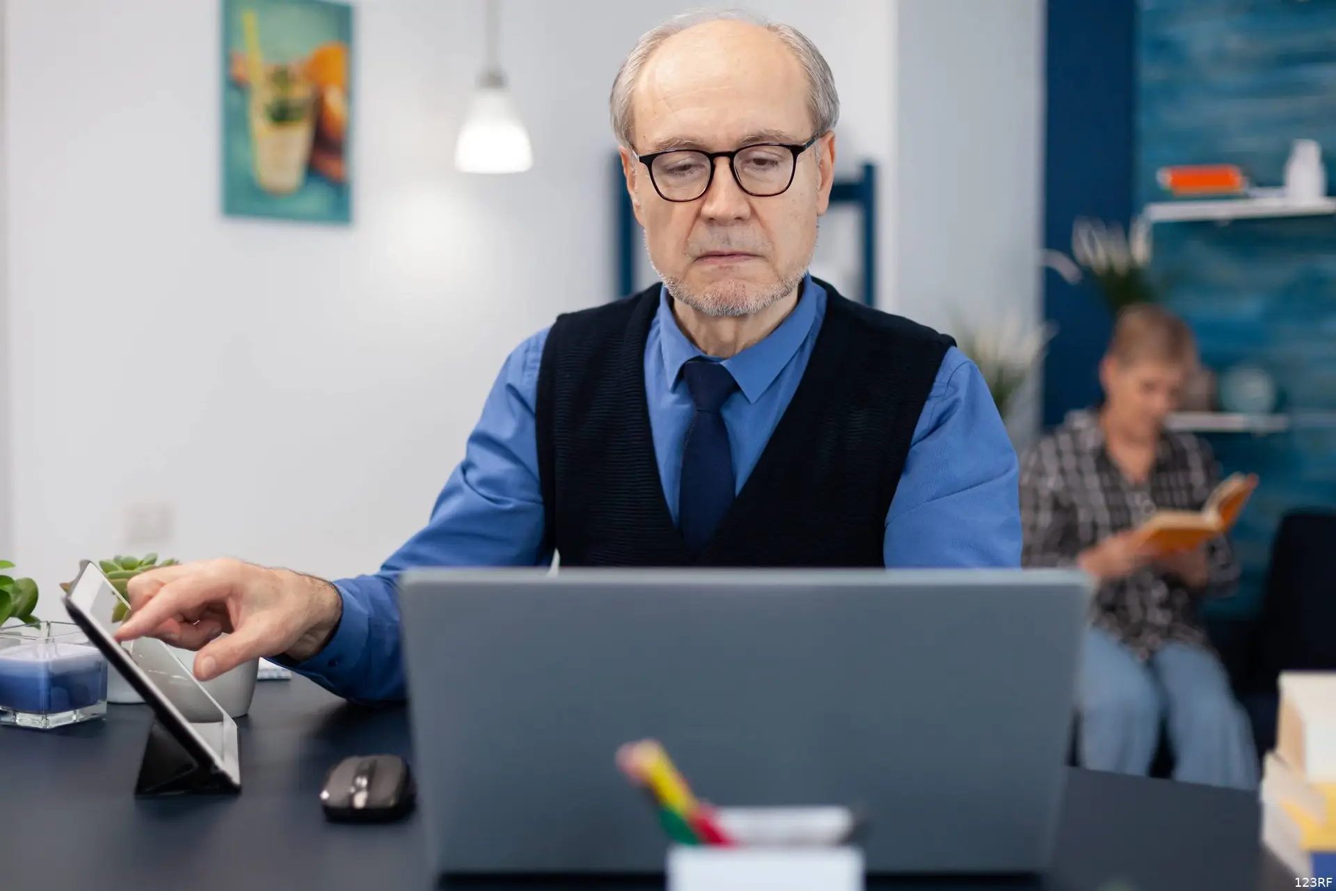Een man van rond de zeventig werkt achter een bureau op een kantoor.