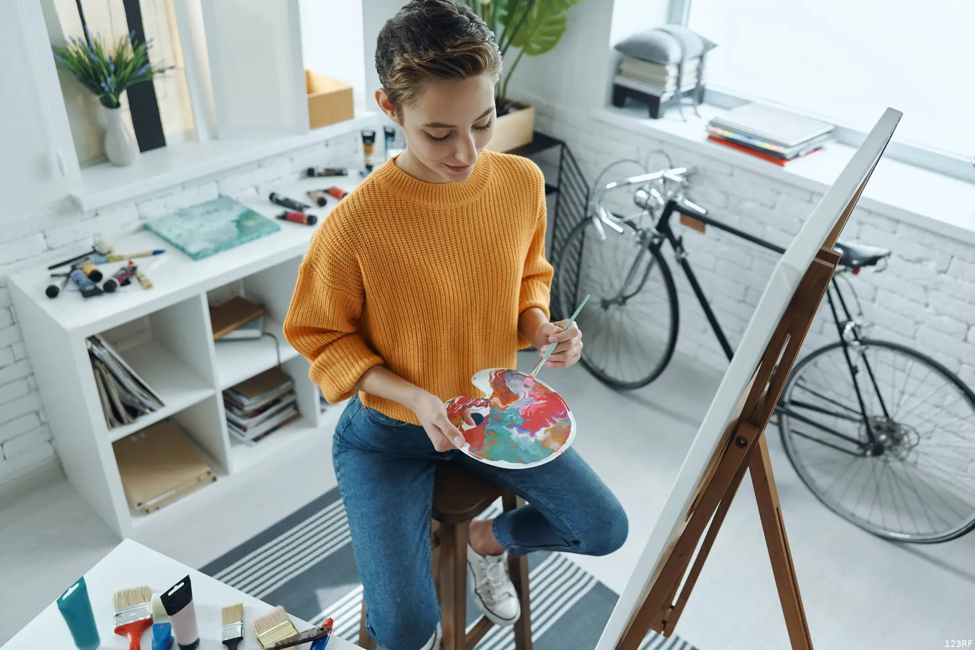 Top uitzicht van mooie jonge vrouw mengen kleuren tijdens het tekenen in kunst studio