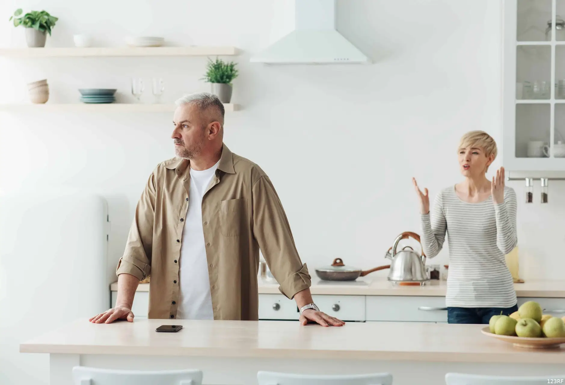 Een man en een vrouw zitten aan de keukentafel en praten na een ruzie.