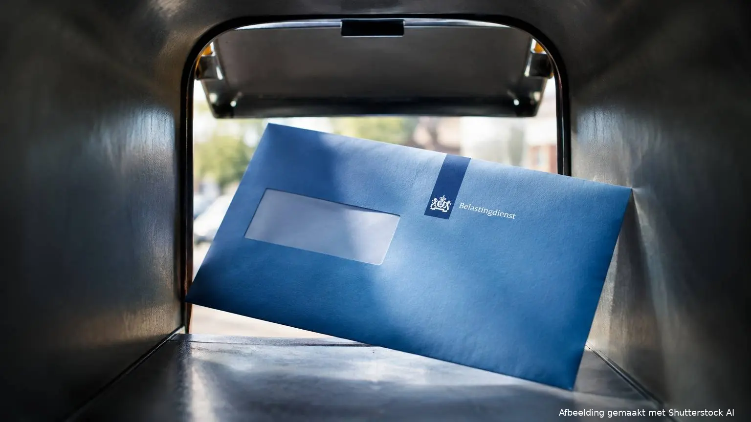 Blauwe envelop van de Belastingdienst bij een brievenbus.