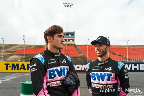 Jack Doohan stands next to Pierre Gasly, chatting during an Alpine marketing event, both dressed in their racing suits.