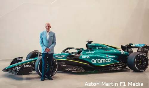 Adrian Newey posing for a picture next to a copy of Aston Martin's 2024 F1 car in a factory at Silverstone on the day of the announcement.