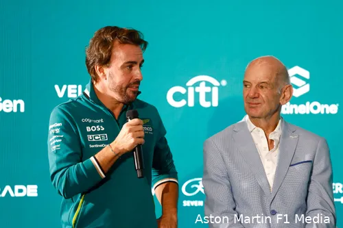 Fernando Alonso speaking to the media with Adrian Newey beside him at an Aston Martin press conference, partner logos in the background.