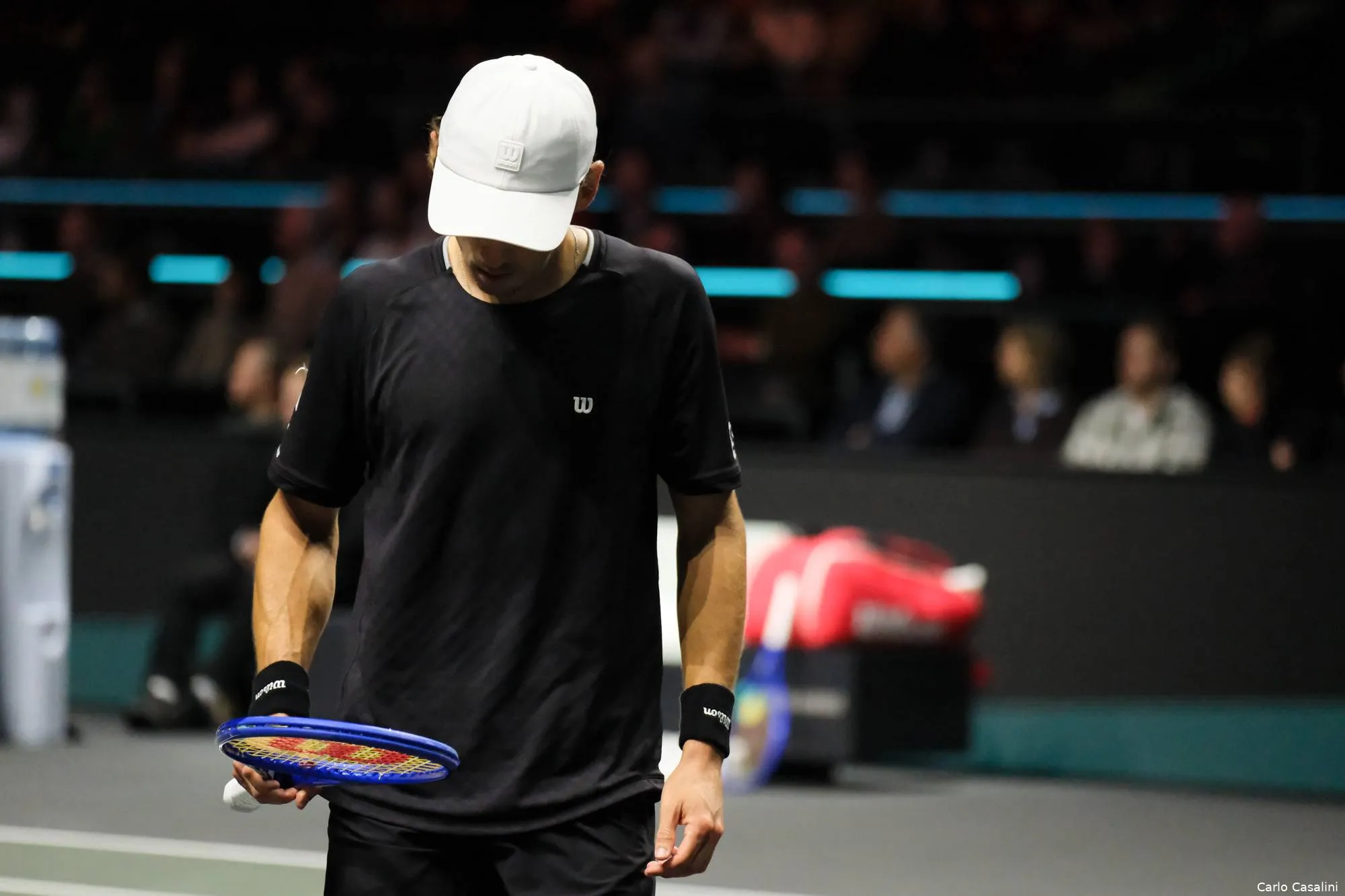 Alex de Minaur looks at racquet.