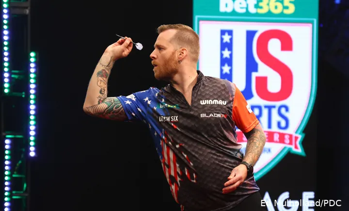 Jules van Dongen aims to throw his dart at the board.