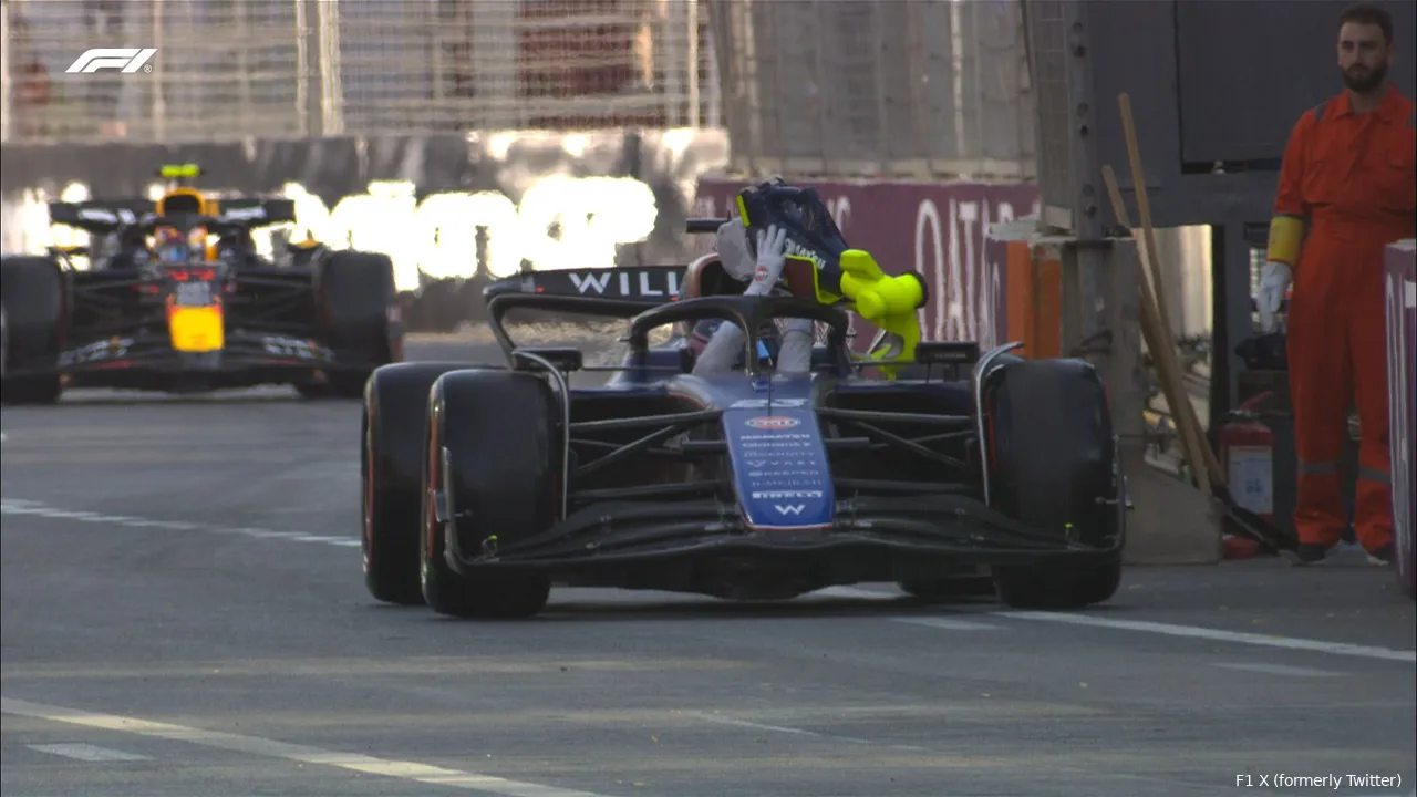 Alex Albon stopped at the pit exit, tossing cooling equipment out of his car, with a marshal standing nearby and Sergio Perez exiting the pits in the background.