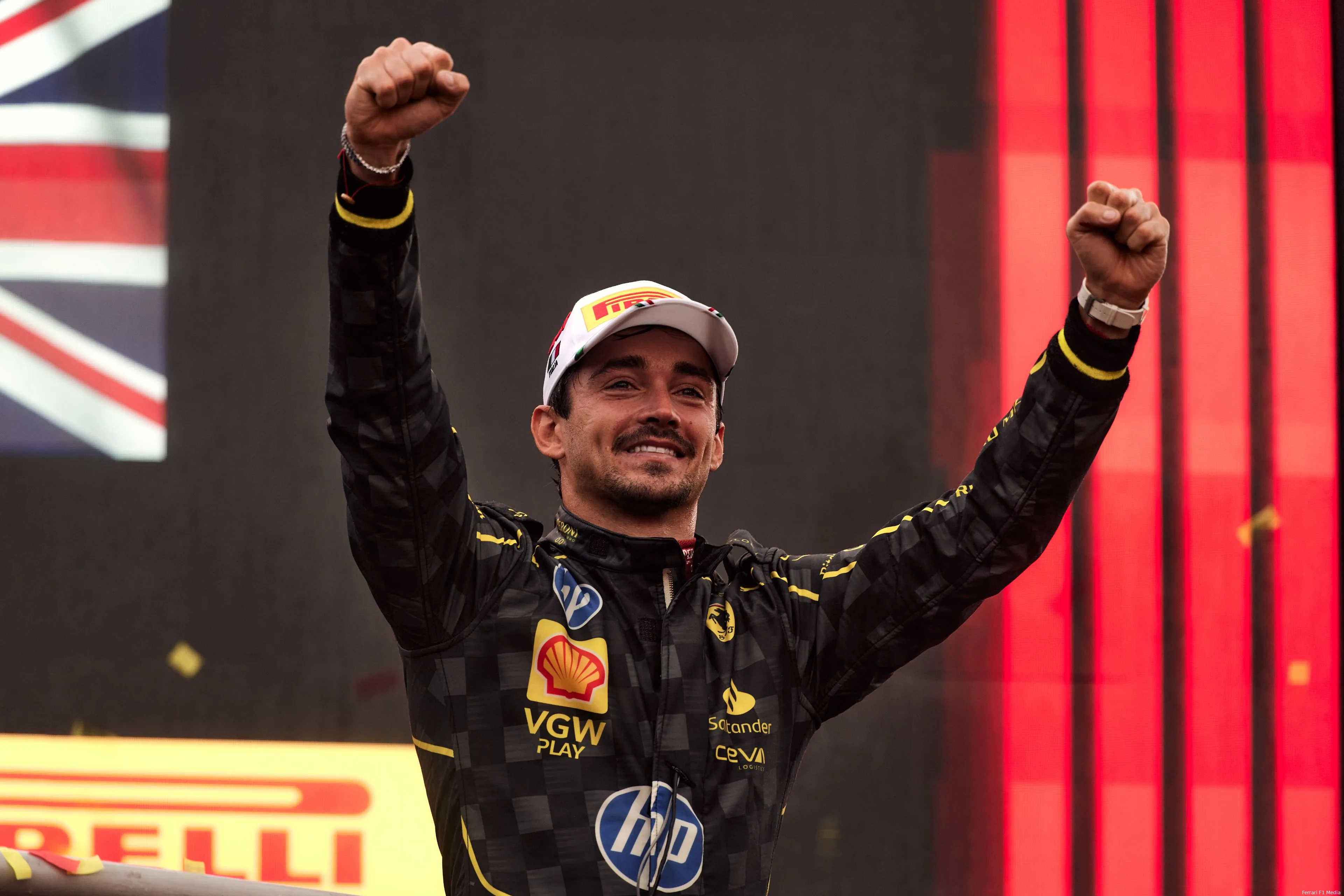 Charles Leclerc celebrates with arms raised on the podium after winning the 2024 Italian Grand Prix at Monza in his special black Ferrari race suit.