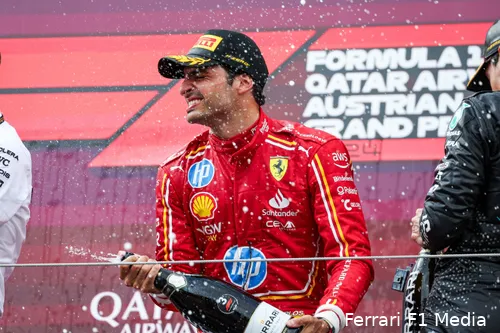 Carlos Sainz celebrates his P3 finish on the podium after the 2024 Austrian Grand Prix, spraying champagne with joy.