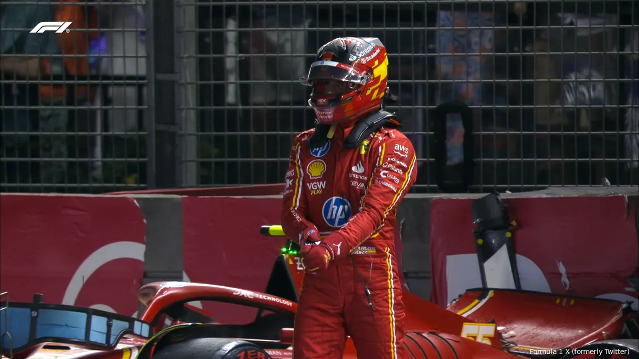 Carlos Sainz walking away from his crashed Ferrari in the background, heading towards the pit lane during the 2024 Singapore Grand Prix qualifying.